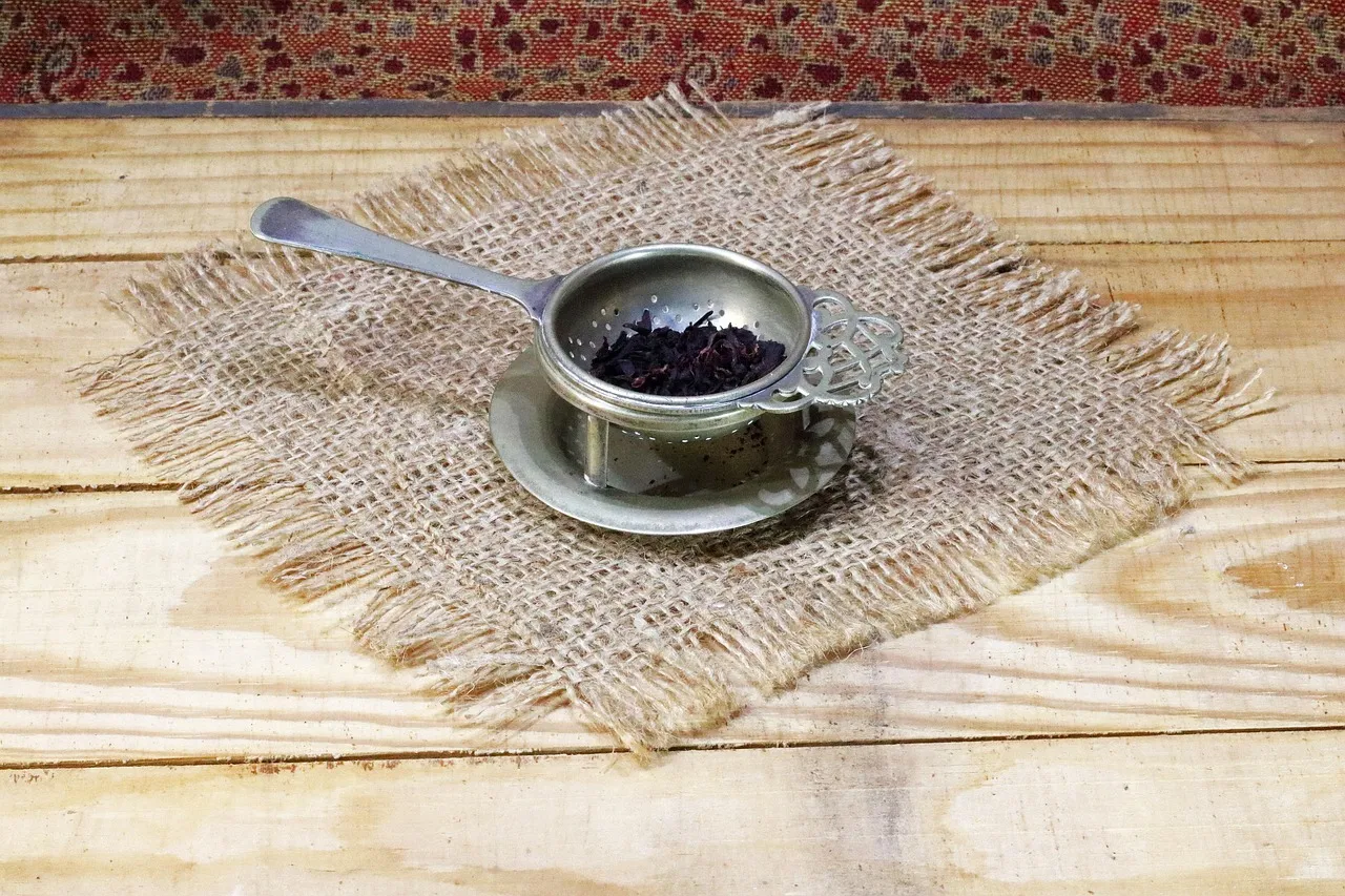 A brass tea strainer on a saucer on a wooden table