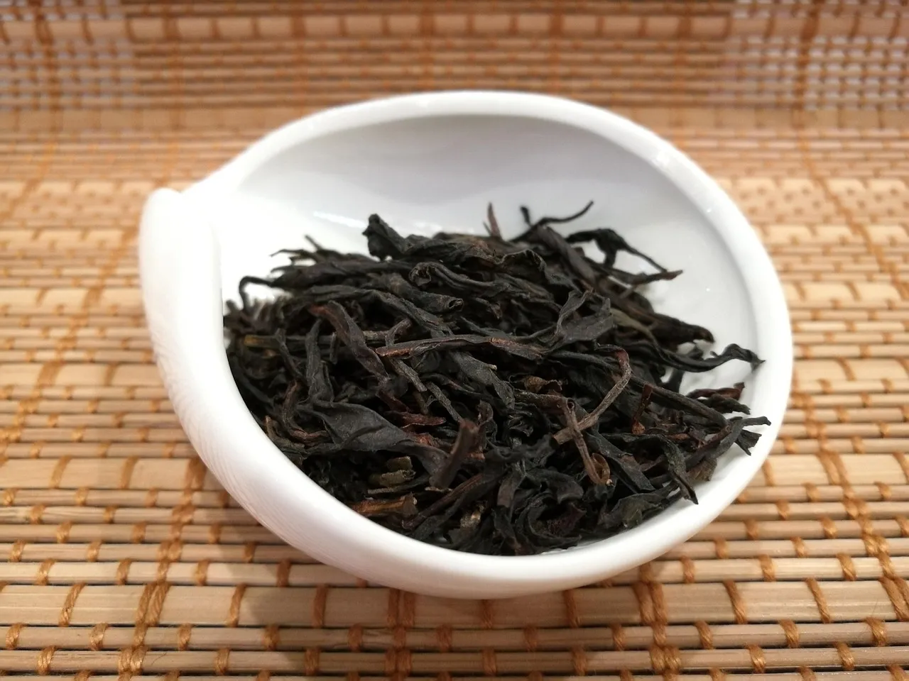 Twisted dark oolong leaves in a white porcelain dish