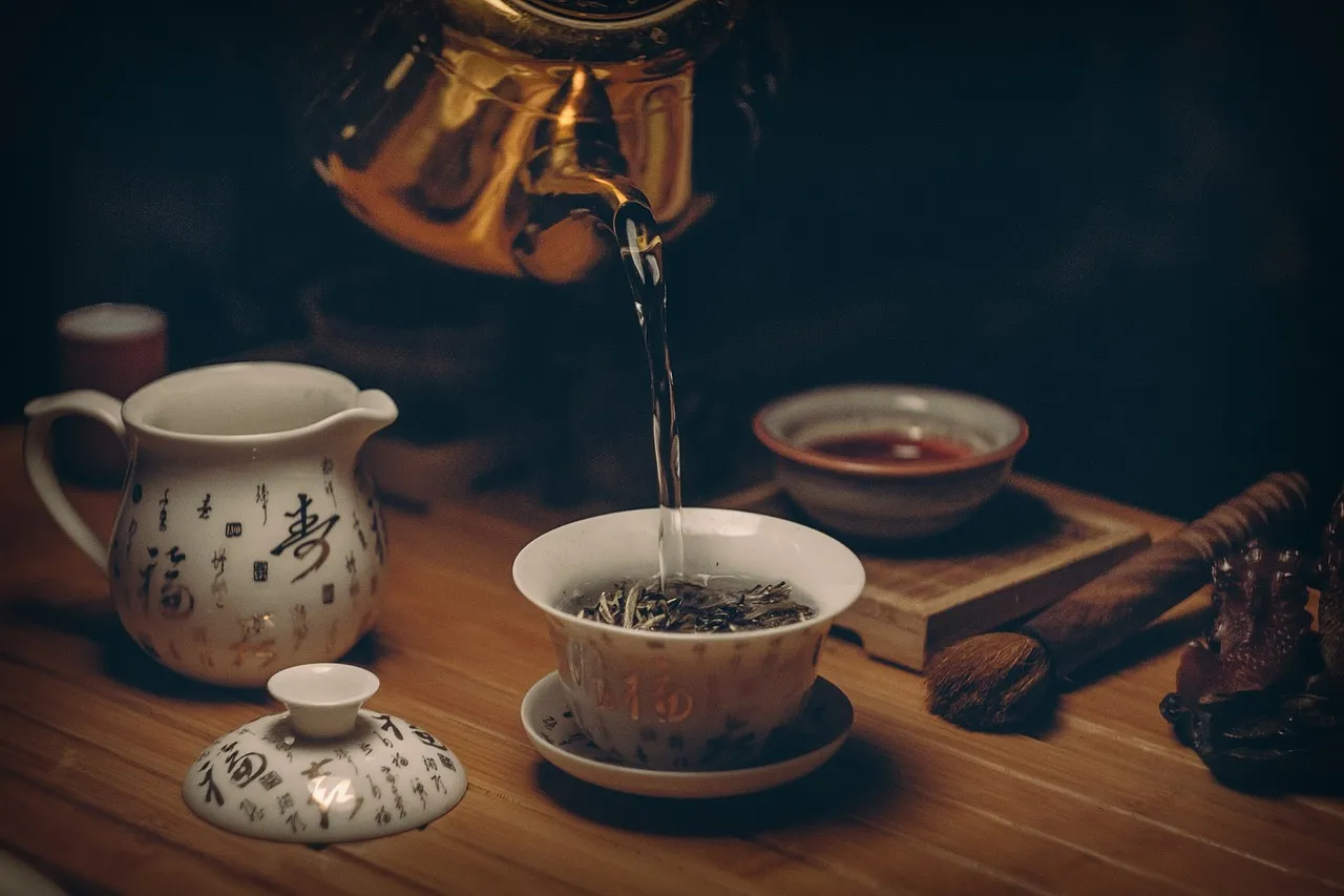 Tea being poured from a pot into a small cup